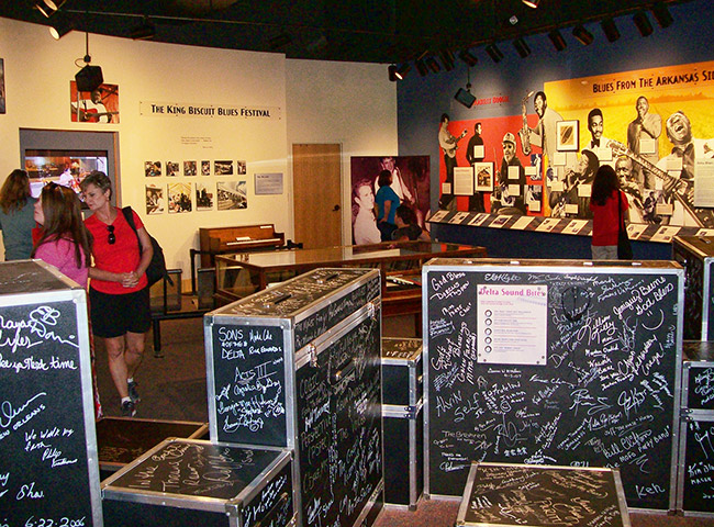 White women in museum with autographed instrument cases and display cases