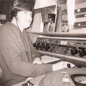Young white man with headphones sitting before radio equipment
