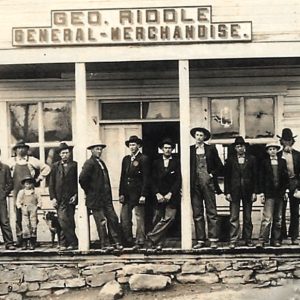 People standing on porch beneath sign stating "George Riddle General Store"