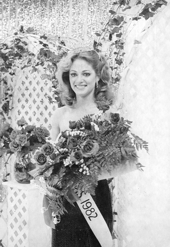 White woman wearing sash and holding bouquet of flowers