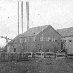 Two wooden buildings with smokestacks