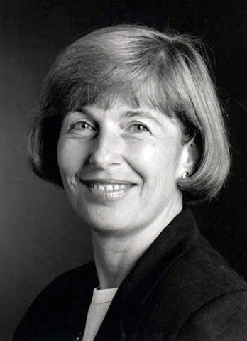 White woman with short hair smiling in suit