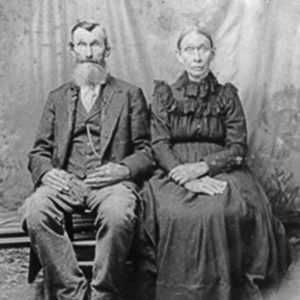 Old white man in suit seated next to old white woman in dress