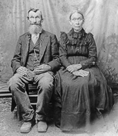 Old white man in suit seated next to old white woman in dress