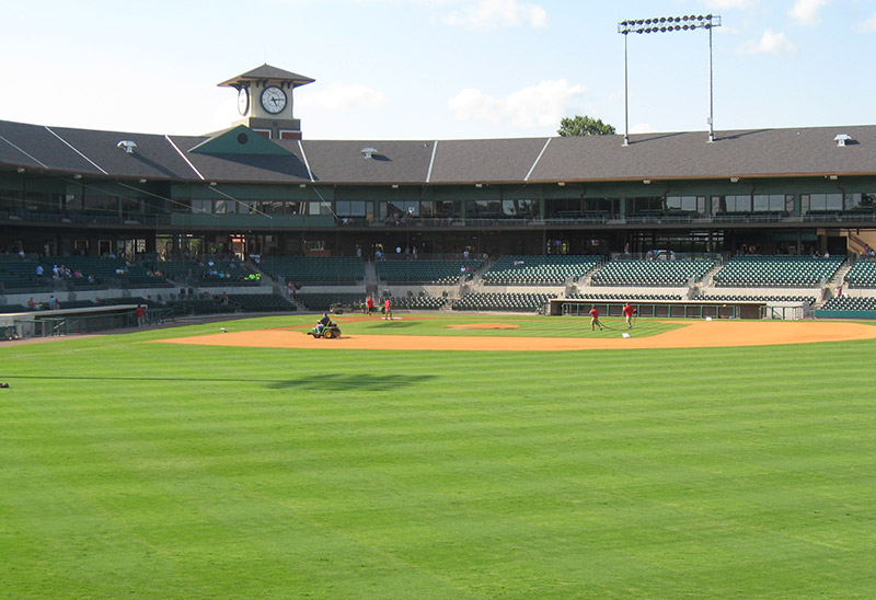 View of infield at multistory baseball stadium with clock tower in the background