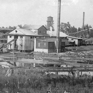 Industrial buildings with smoke stacks and water tower on muddy ground