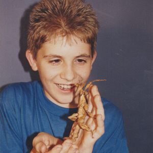 Young white boy holds large insect