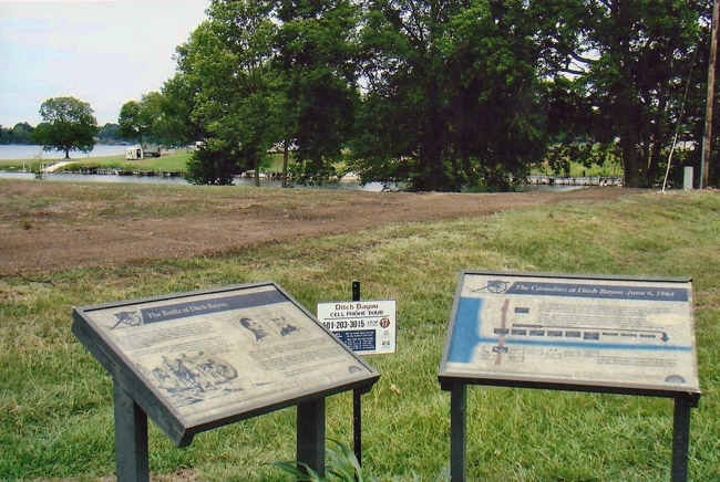 Field and lake with flat interpretation panels and trees