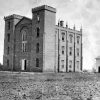 Tall castle like building with arched windows and small shed