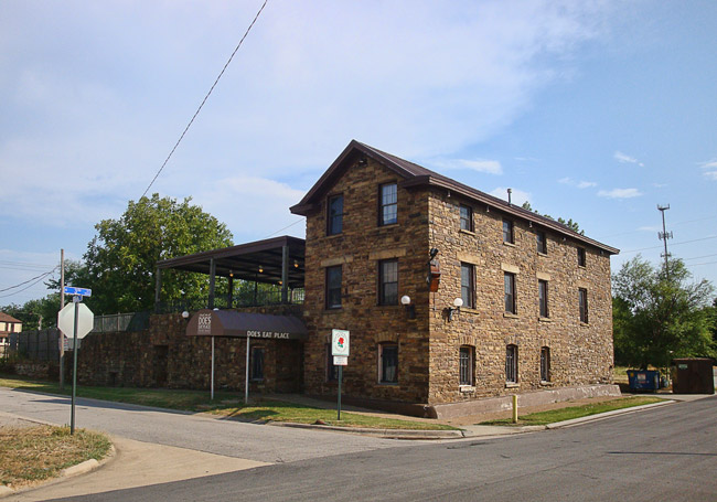 Three-story stone building with modern elevated balcony area on street corner