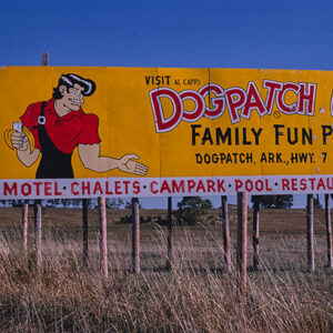 Cartoon of white man eating banana on yellow and white billboard with red and black text
