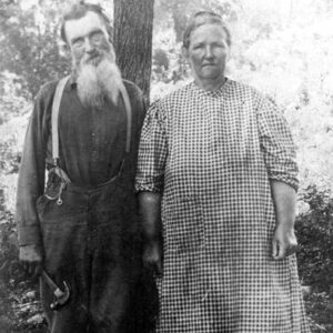 Old white man in overalls with hammer and old white woman in checkered dress