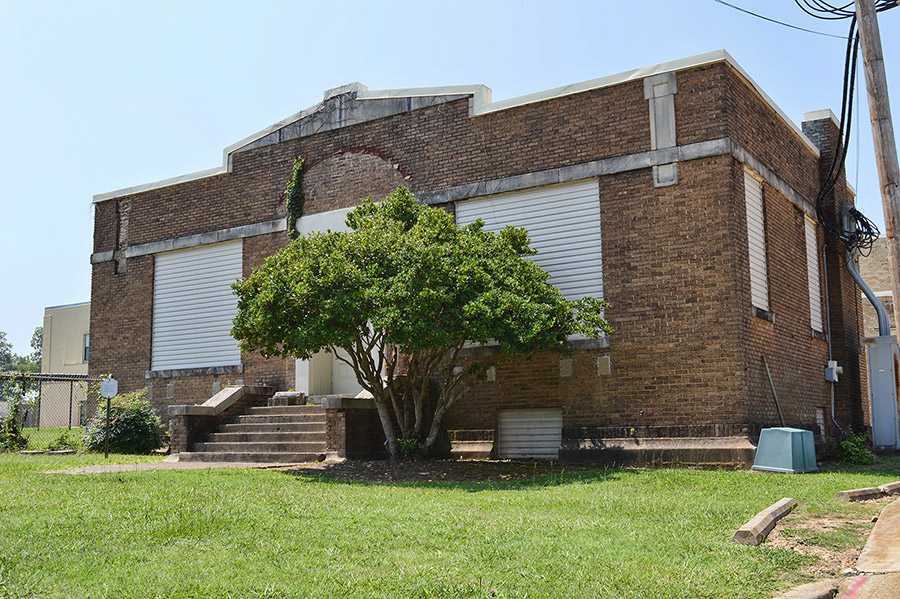 Brick building with covered windows and tree in front