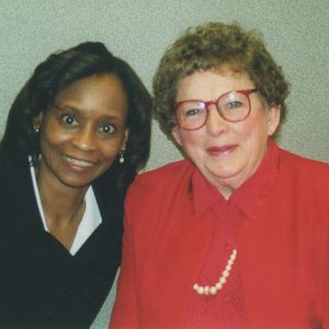 African-American woman smiling with white woman in red glasses smiling in red suit