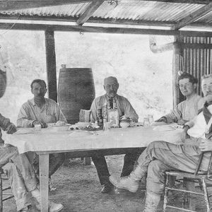 Group of white men and woman sitting around a table in pavilion