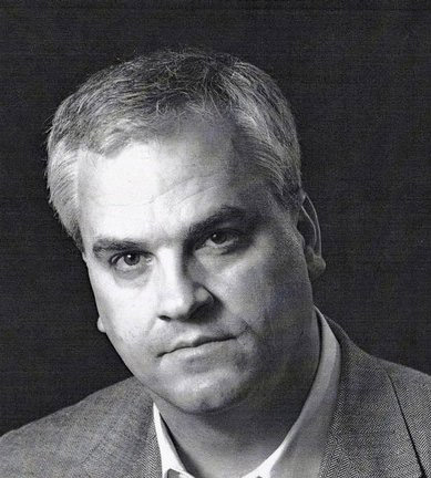 black-and-white photo of white man with serious expression in suit jacket