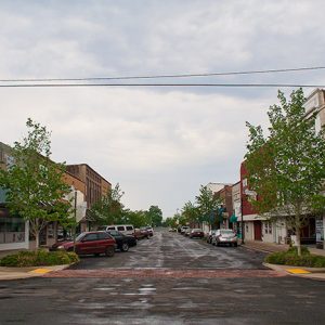 Looking down street with parked cars and multistory brick storefronts on either side