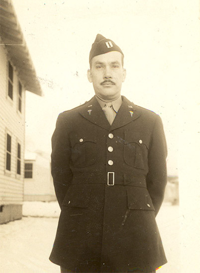man with dark mustache standing in military uniform with cap