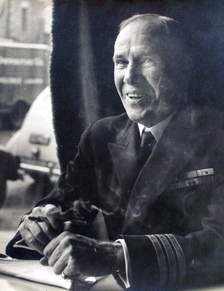 Portrait white man seated by window smiling smoking in military officer jacket