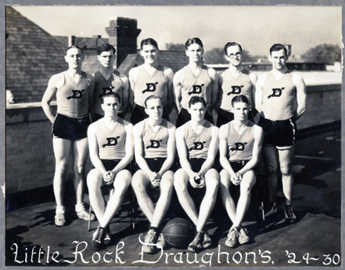 Group of young white men pose for a group photo in shorts and tank tops with basketball