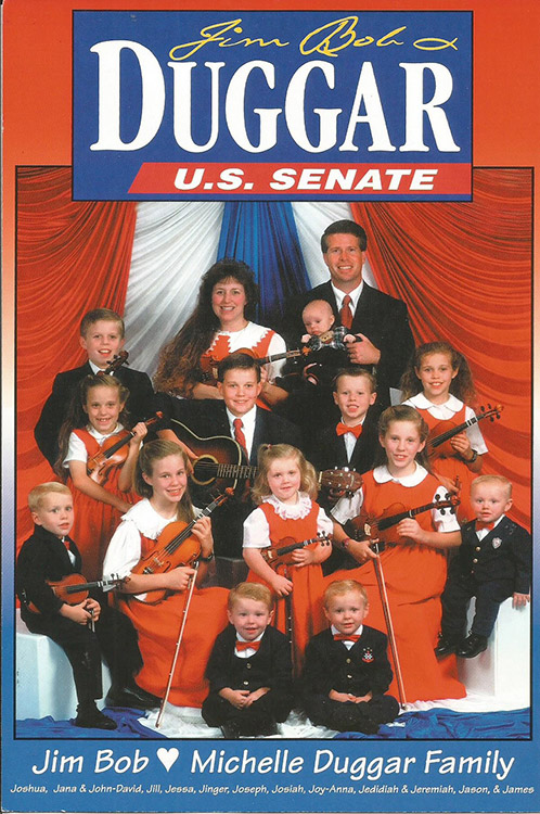 White man in suit and woman in dress with children holding musical instruments below "Jim Bob Duggar U.S. Senate" banner