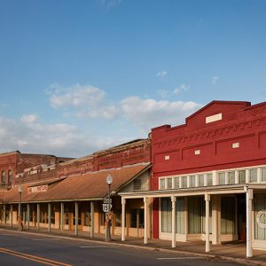 Row of storefront buildings with covered sidewalk on town street