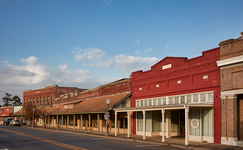 Row of storefront buildings with covered sidewalk on town street