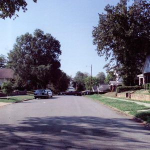 Brick and paneled houses and parked cars on street in residential neighborhood