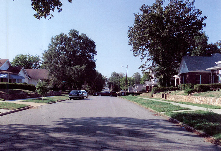 Brick and paneled houses and parked cars on street in residential neighborhood