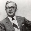 White man with glasses in suit and striped tie