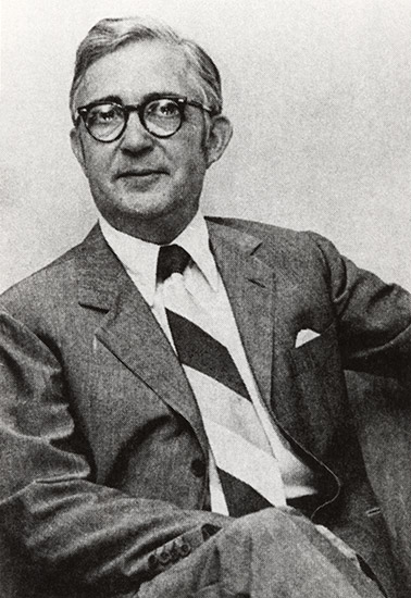 White man with glasses in suit and striped tie