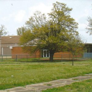 Single-story brick school buildings with fenced-in yard
