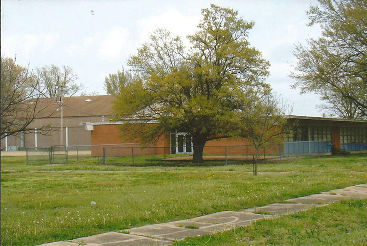 Single-story brick school buildings with fenced-in yard
