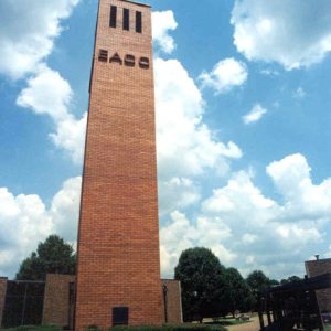 Solid brick tower with large "E.A.C.C." letters three vertical windows at top on brick campus