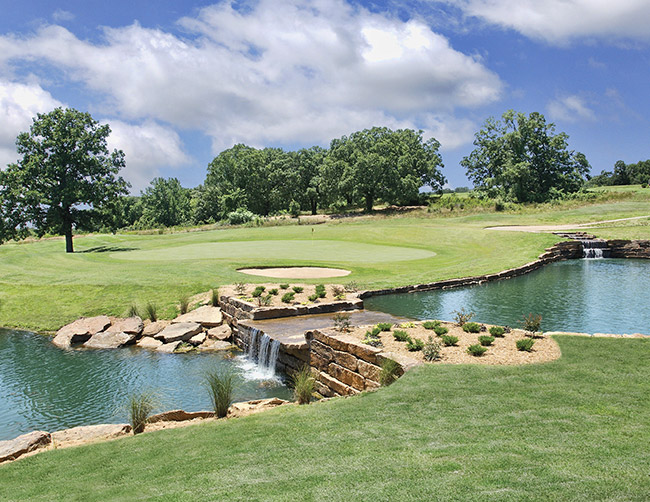 Brick dam and water features at golf course with trees and sand pits in the background