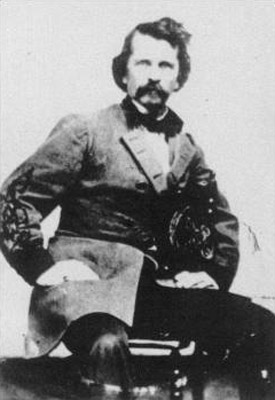 Portrait white man wavy hair mustache military uniform seated posing hands on lap