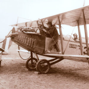 White man servicing a biplane labeled "Eberts Field Lonoke Ark" with pilot in seat and another man standing at the side