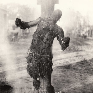 Front view of burned body of African-American man chained to pole