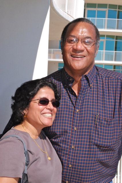 African-American man with glasses and woman with sunglasses smiling on balcony of multistory building