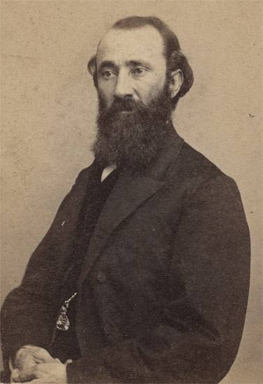 White man with long dark beard in suit and tie