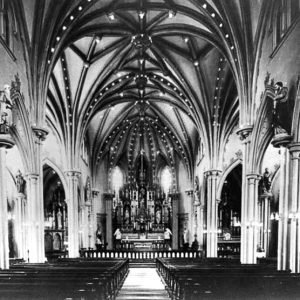 Interior of multistory church sanctuary with wooden pews and altar under vaulted ceiling