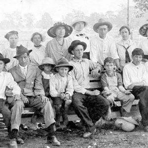 Group of white women and children sitting on and standing behind wooden bench