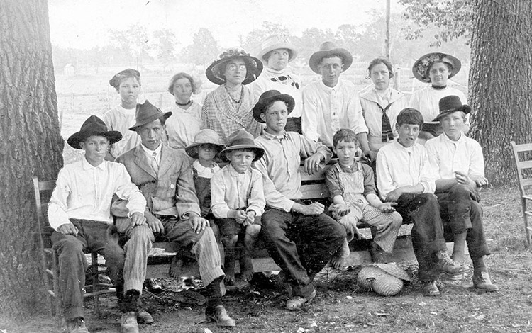 Group of white women and children sitting on and standing behind wooden bench