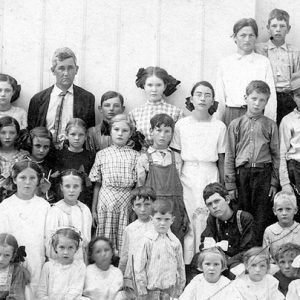 Group of white children with white man in suit and tie