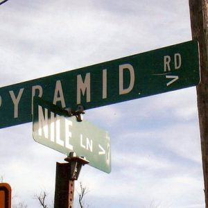 Street signs for "Pyramid Road" and "Nile Lane" with telephone pole and blue skies