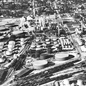 Aerial view of oil refinery with round tanks and buildings with town in the background