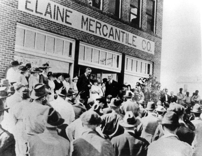 White men in suits talking to a crowd outside the Elaine Mercantile Co.