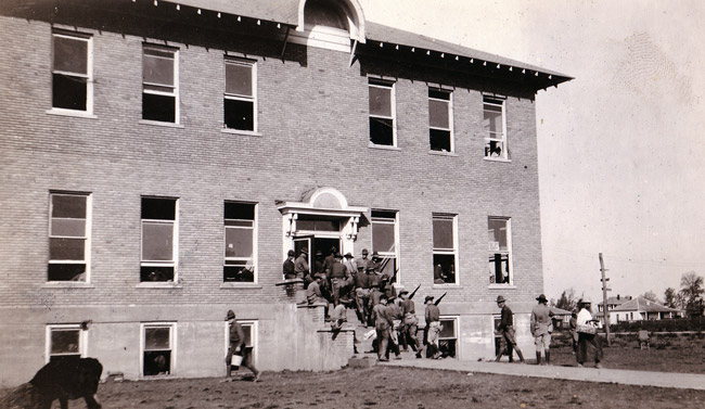 Group of soldiers in uniform on steps of multistory brick building