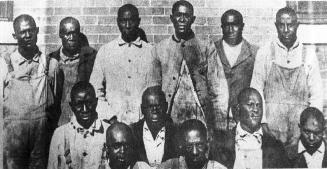 Group of African-American men standing and sitting before brick wall