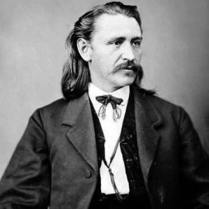 man with swept-back long hair and mustache in suit and small bow tie